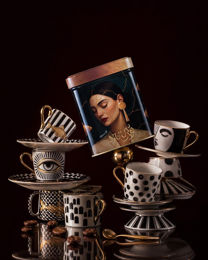 Golden Aura artwork tin resting on stacked porcelain cups