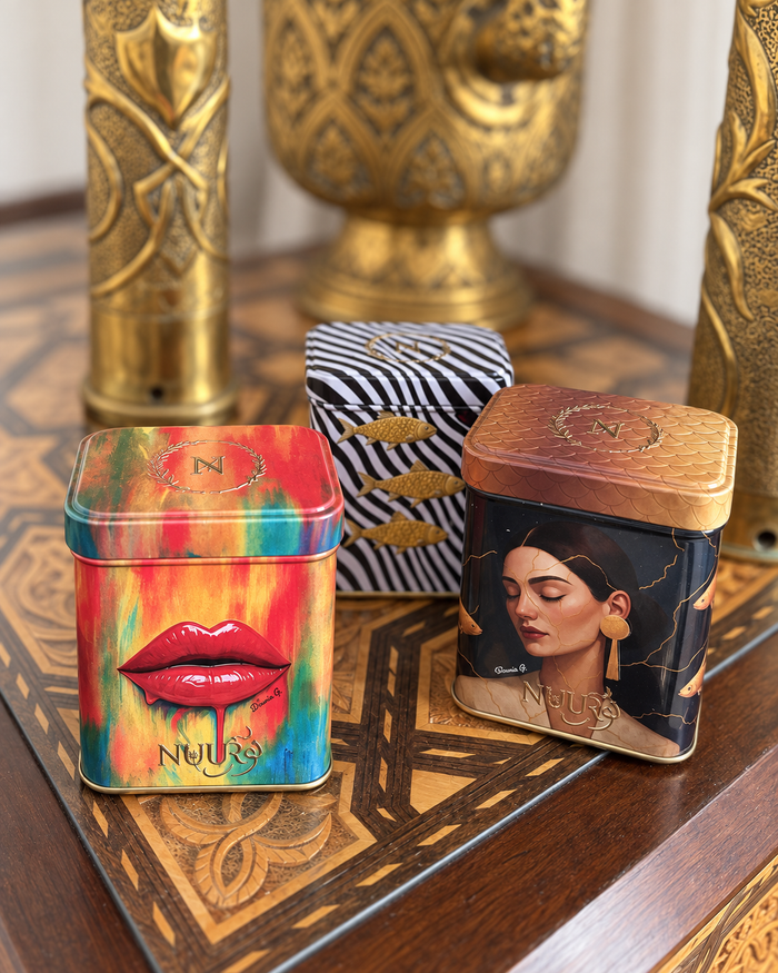 Three NUUR art tins on an inlaid wooden table